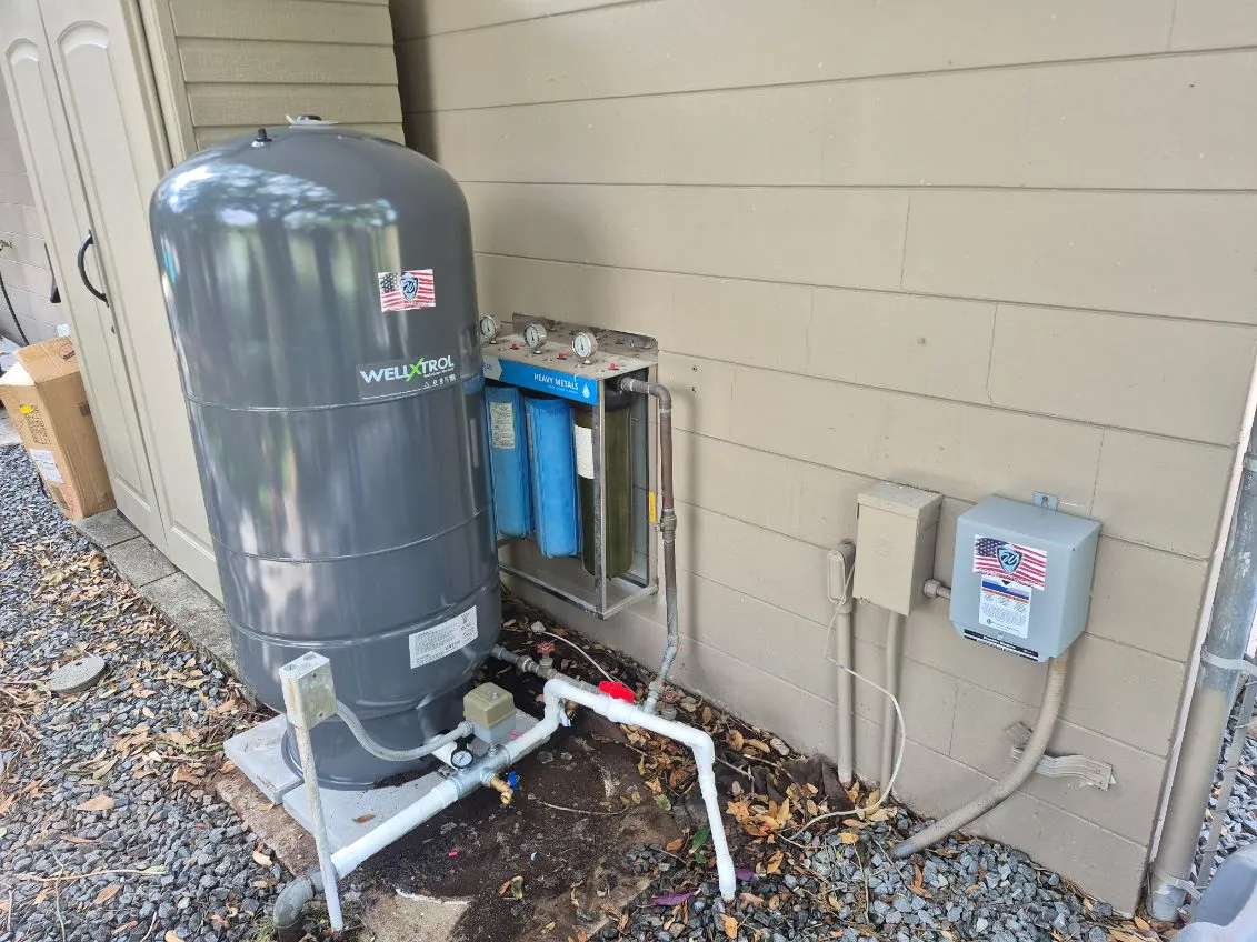 New pressure tank and water filtration units installed beside a home